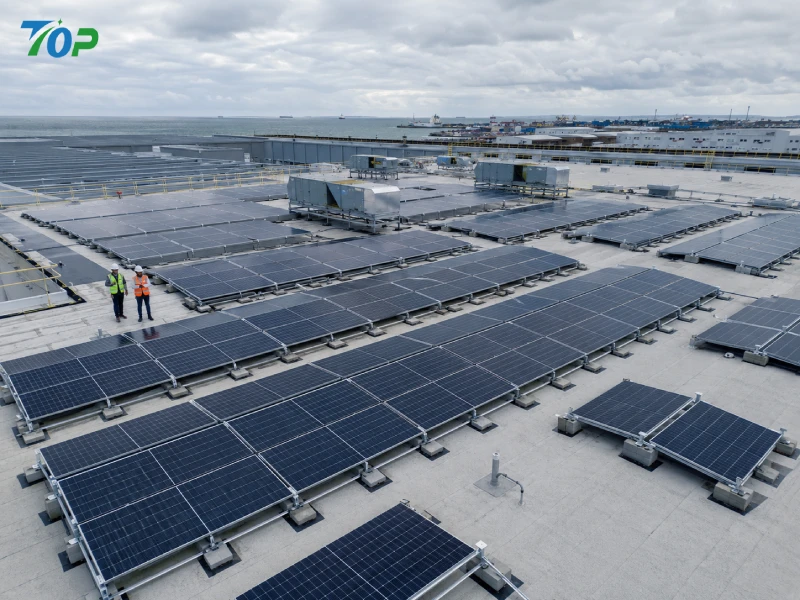 East-West flat roof solar ballast mounting system installed on coastal industrial warehouse rooftop with aerodynamic wind deflectors